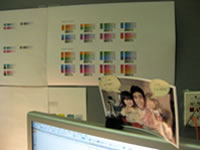 デスクの壁。カラーチャートと、娘さん達との写真